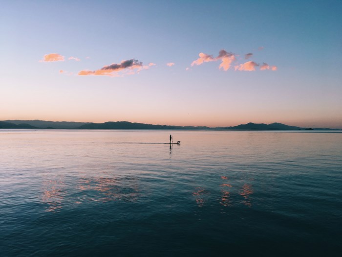 Person paddle boarding on a lake at dusk