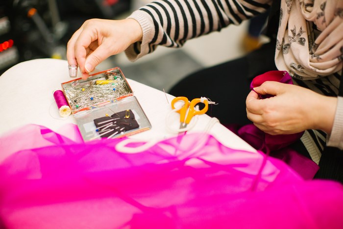 Person sewing with thread, pins, and scissors
