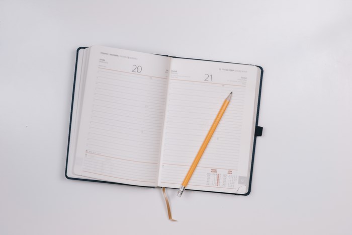Open diary with pencil on white background