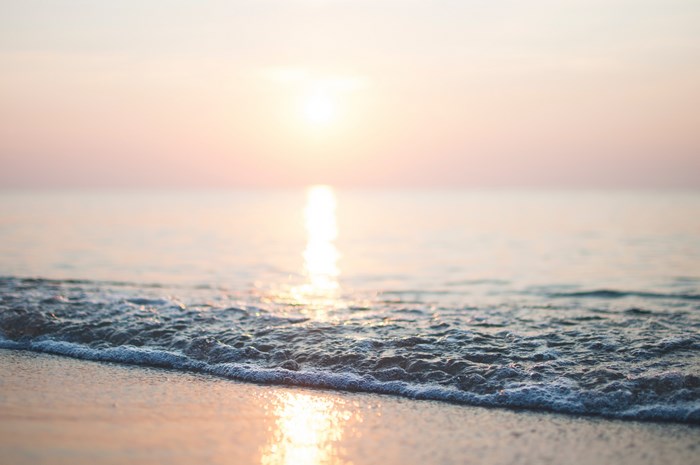 Sunrise over the ocean with gentle waves on the shore