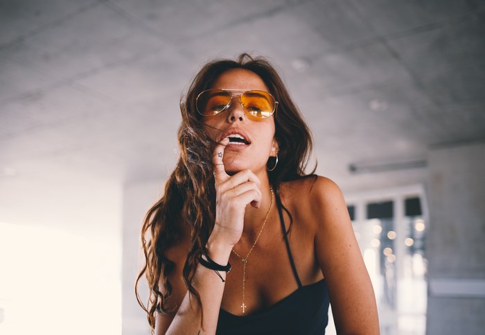 Woman with sunglasses and finger tattoo posing indoors
