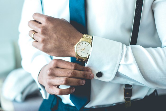 Man in white shirt adjusting cufflinks and watch
