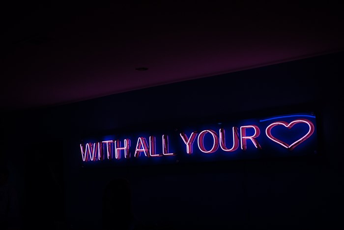 Neon sign with heart and text "WITH ALL YOUR"