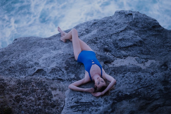 Woman in Blue Swimsuit Lying on Rocky Shore