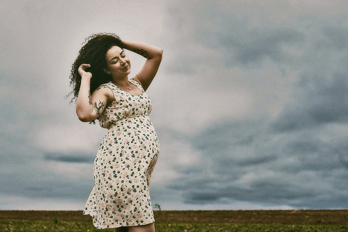 Pregnant woman with curly hair in a floral dress