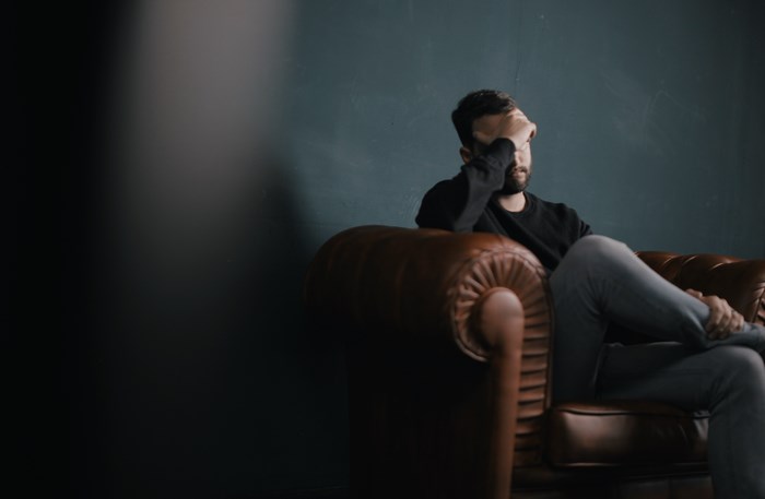 Man sitting on a leather couch, looking stressed