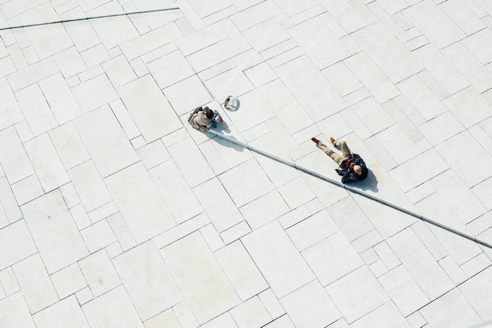 Two people on a white tiled geometric piazza