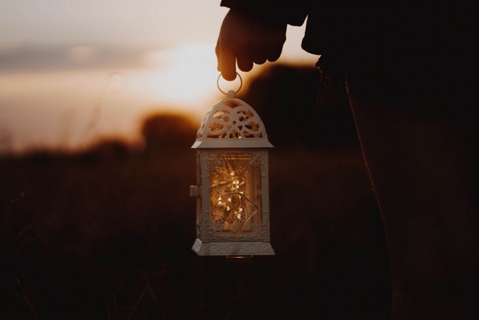 Hand holding a lantern at sunset