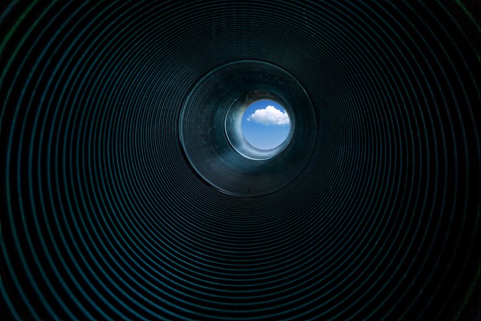 View of the sky through a dark tunnel
