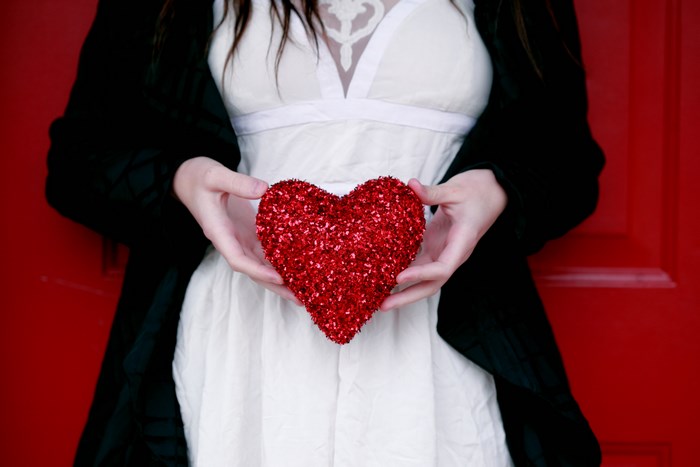 Woman holding a red heart in front of a red door