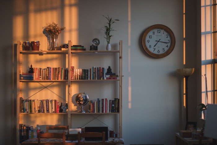 Bookshelf with books, clock, and sunset light
