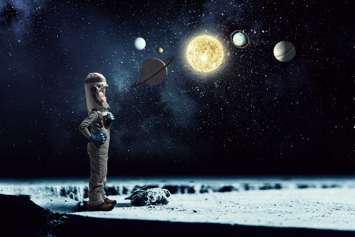 Child in astronaut costume looking at solar system