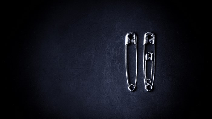 Three safety pins on a dark background