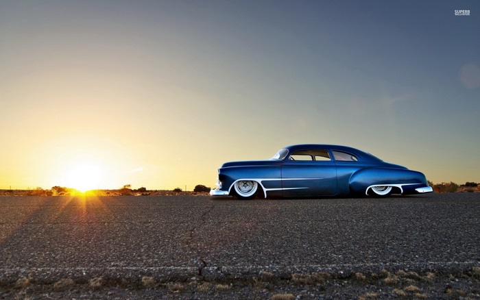 Blue hot rod car at sunset on a road