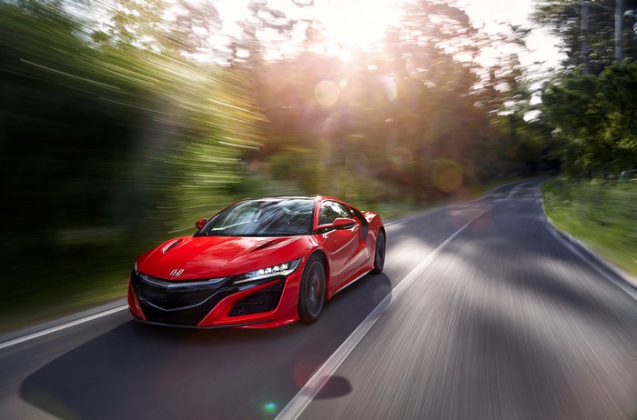 Red Honda NSX driving on a forest road