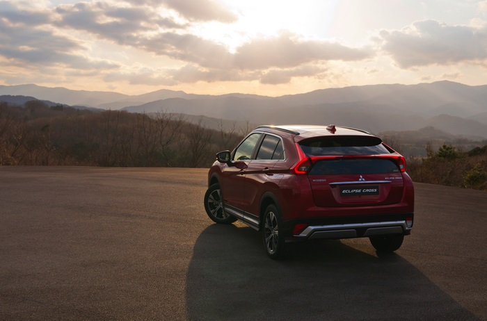 Red Mitsubishi Eclipse Cross SUV on a mountain road at sunset