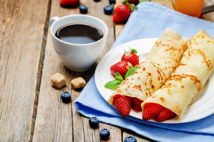 Breakfast with coffee and crepes with strawberries