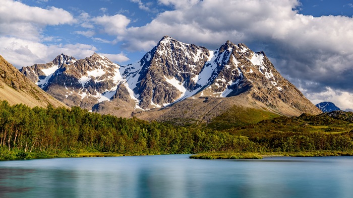 Snow-capped mountains over a lake and forest 4K