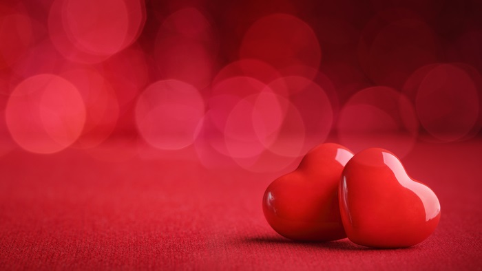 Two red hearts on a red background with bokeh