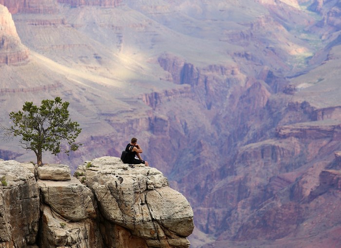 Man sitting on cliff edge overlooking Grand Canyon