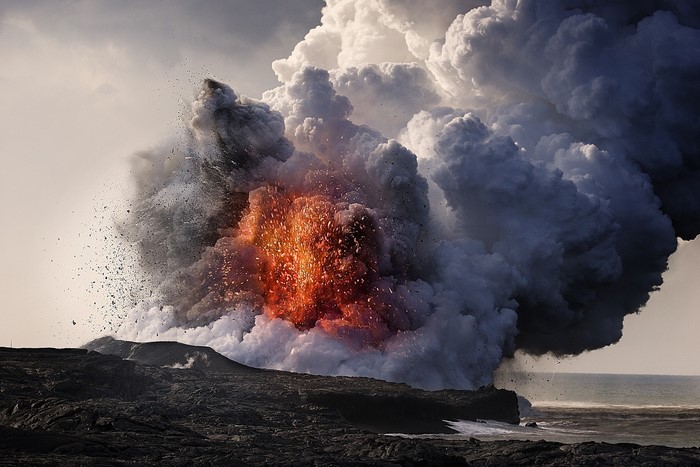 Volcano eruption with lava, smoke, and ash over the sea