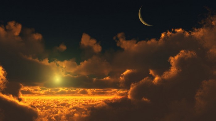 Crescent moon over clouds at sunset