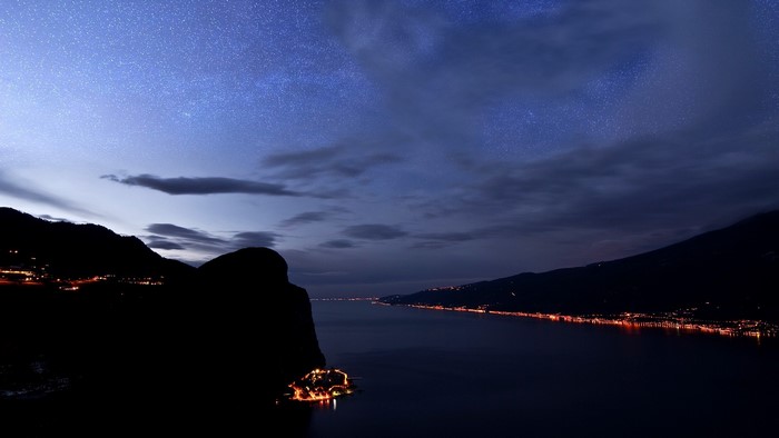 Night sky over a lake with illuminated towns