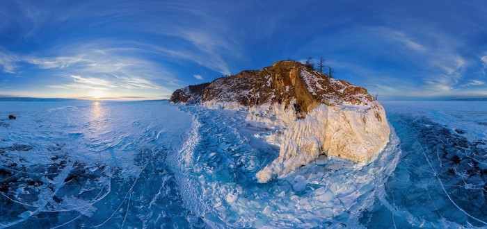Winter sunset over frozen Lake Baikal with rocky island