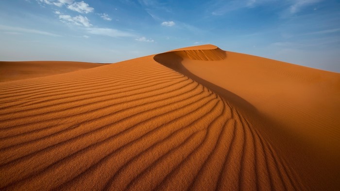 Desert sand dunes under a blue sky