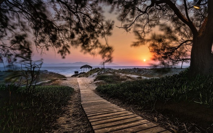 Wooden walkway to a beach hut at sunset