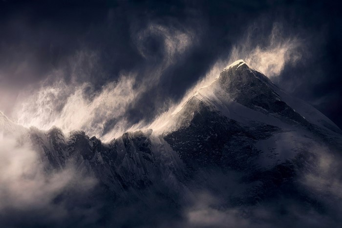 Snowy mountain peak with wind and clouds