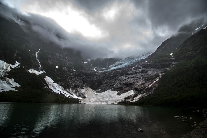 Glacier and lake under dark clouds in Norway