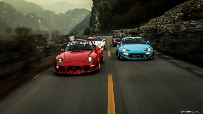 Group of modified sports cars driving on a mountain road