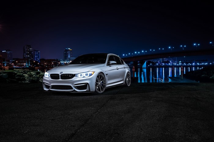 Silver BMW M3 Sedan parked at night by a city waterfront