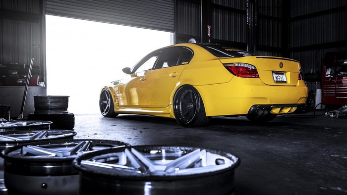 Yellow BMW E60 M5 in a garage with rims