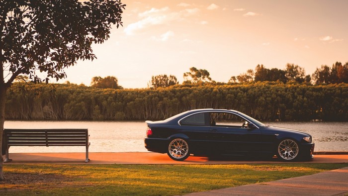 Dark blue BMW E46 coupe by the river at sunset