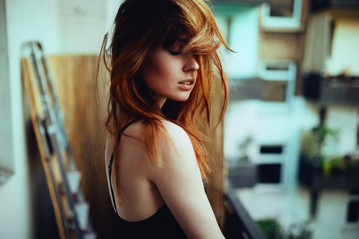 Redhead woman with hair in face on balcony