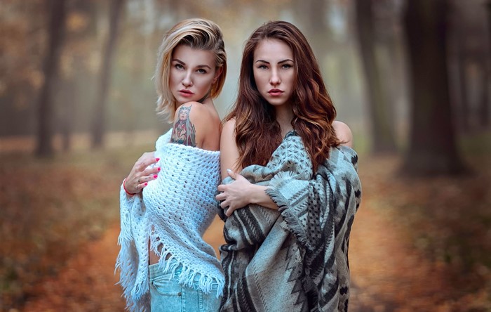 Two women wrapped in blankets in a forest