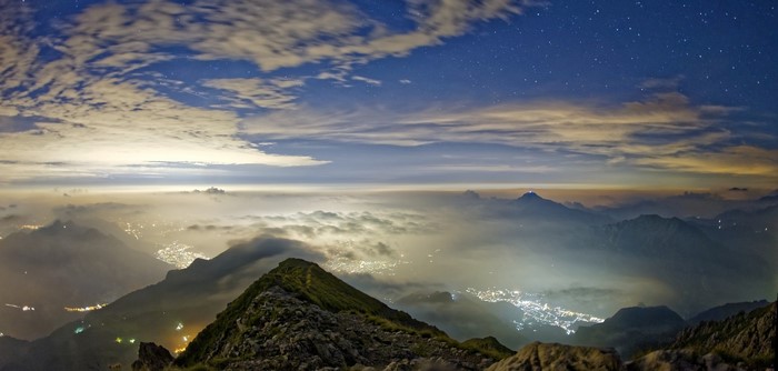 Mountain valley at night with city lights and stars