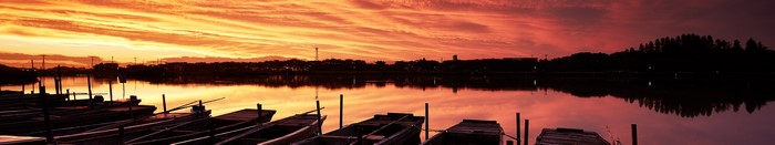 Panoramic sunset over a lake with boats