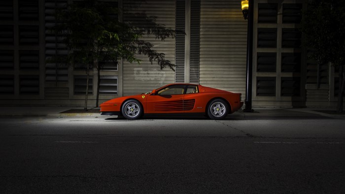 Red Ferrari Testarossa parked on an urban street at night