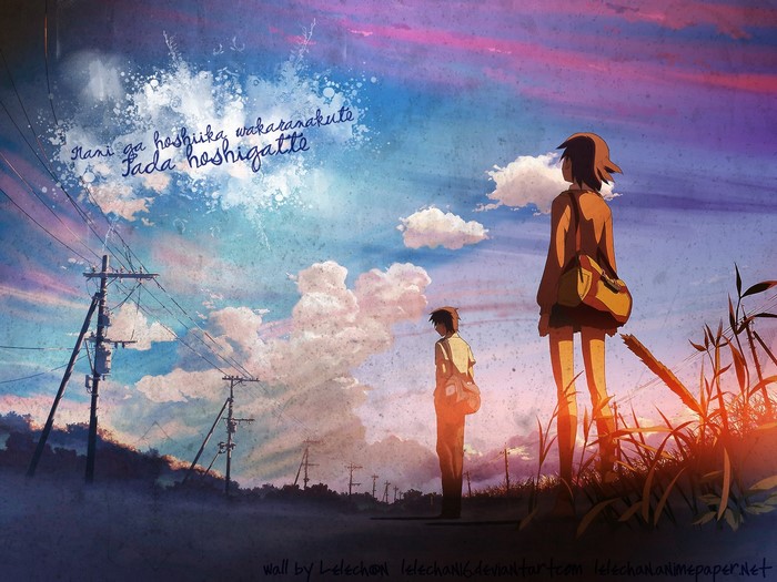 Two people stand in a field at sunset