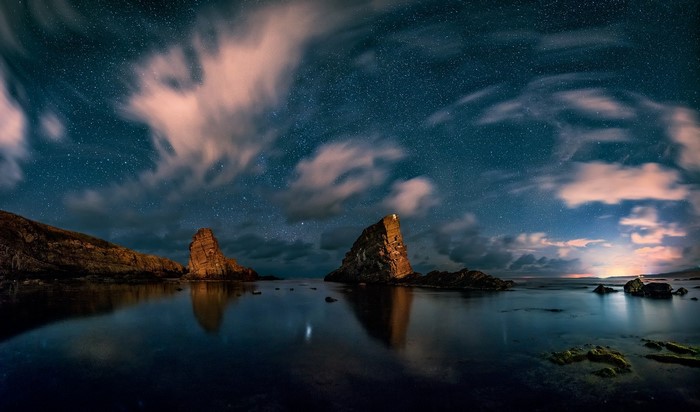 Starry night over rocky coast and sea