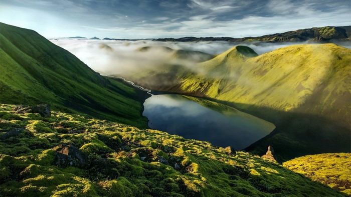 Mossy mountains and lake in Iceland with mist