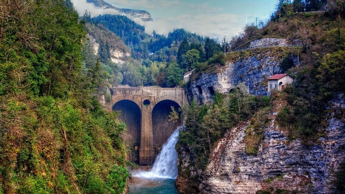 Stone Arch Bridge with Waterfall in Mountain Forest
