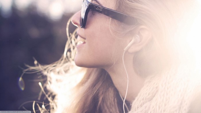 Woman wearing sunglasses and earphones listening to music
