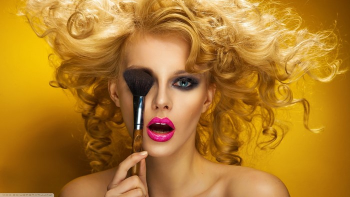 Blonde model with makeup brush and bright lipstick