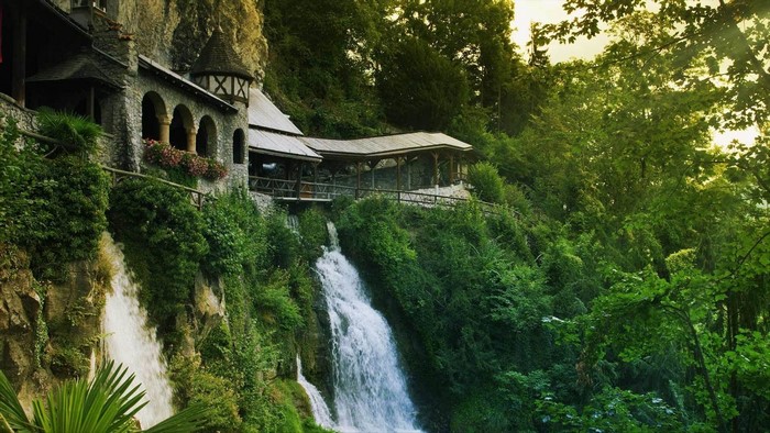 Building on a cliff with waterfalls and trees