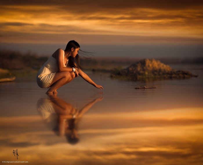Woman touching water at sunset