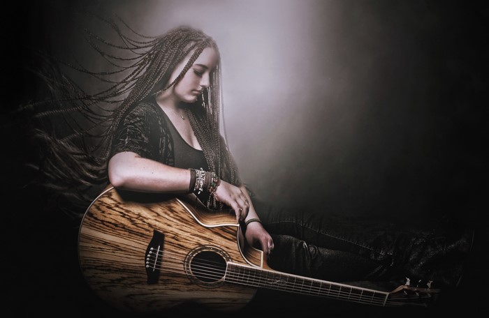 Woman with braided hair playing guitar